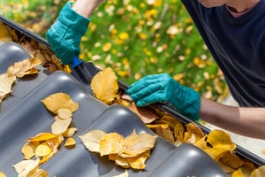 person cleaning house gutters